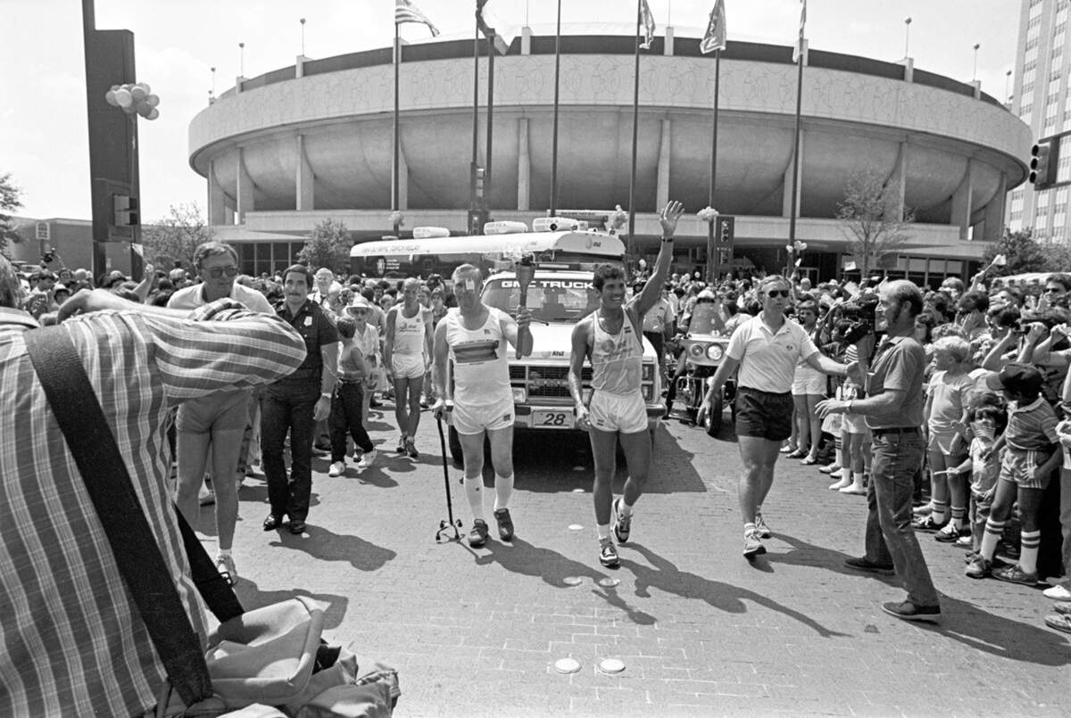 Olympic Torch being carried by Ray Tinnin of Houston, accompanied by David Vigil of San Francisco, in front of the Fort Worth Convention Center on June 14, 1984.